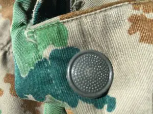 Slightly out of focus close-up of a button, also showing the twill material and the loose register of the camo print. Not bad for over 50 years old. 