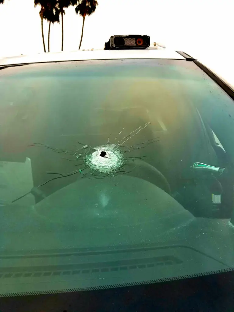 A hole in the windshield shows how a suspect shot at a Huntington Beach police vehicle, hitting an officer, but it deflected off his badge. "The round came through the front windshield of the officers car, struck the officers badge and deflected off," said Jennifer Marlatt, a department spokeswoman.