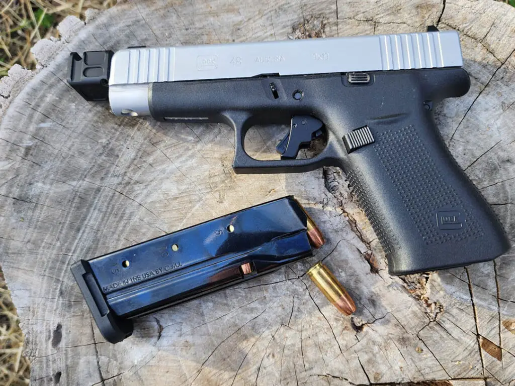 Glock 48 on a log with full magazine of bullets