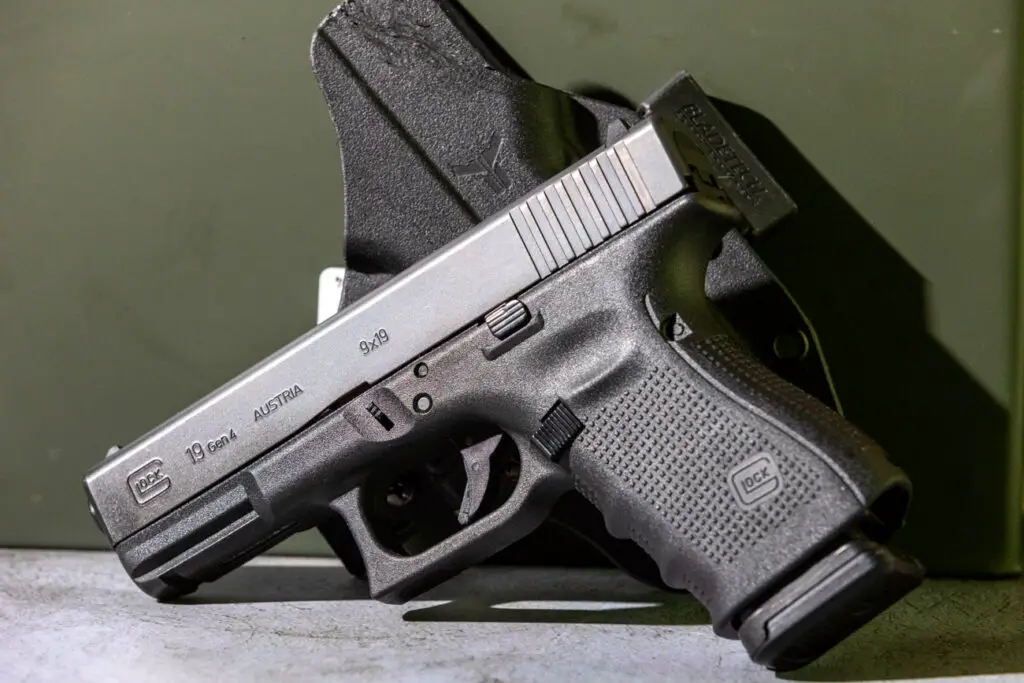 Glock 19 pistol sitting on its side in front of holster