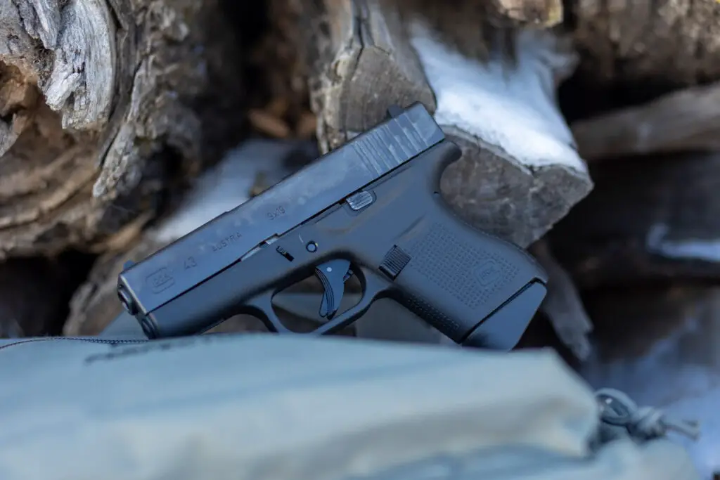 Glock 43 side view next to some wood logs